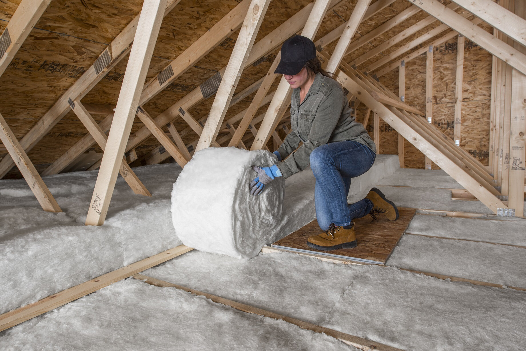 a woman installs johns manville insulation in an attic